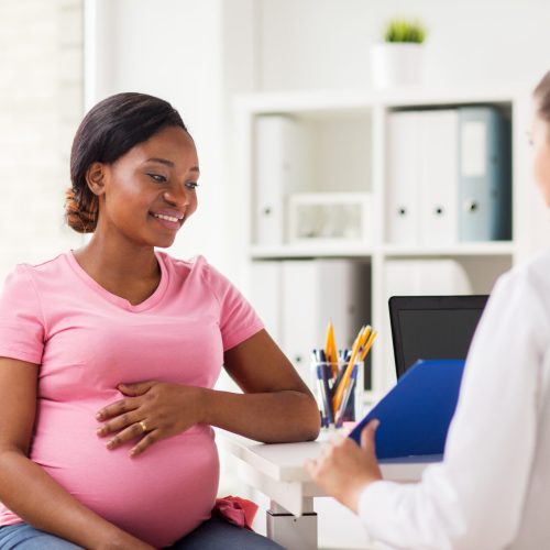 Southern California Fertility Center | About pregnancy, medicine, healthcare and people concept - gynecologist doctor with clipboard and happy pregnant african american woman meeting at hospital